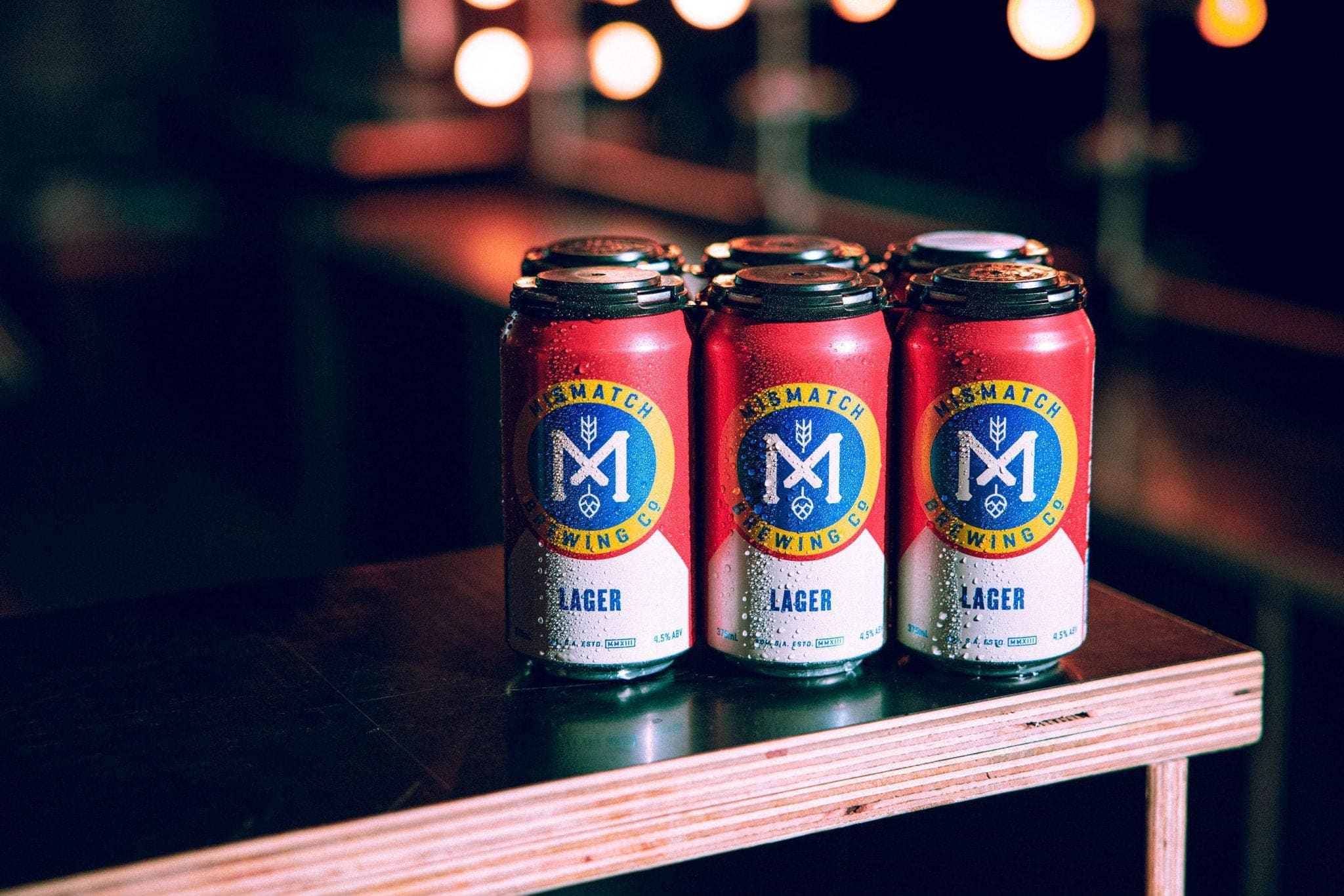 Mismatch Lager cans on a bar at night